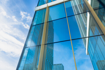 The blue sky is reflected in the windows of a modern office building. Architecture and exterior of contemporary houses