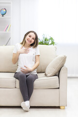 Fototapeta premium Photo of pregnant woman wearing casual clothes and holding childish clothes in hands.