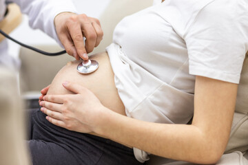 Cropped photo of doctor with stethoscope going to exam the pregnant woman.