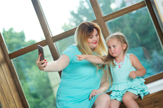 The girl and her mom look at the phone and take a selfie. Mobile technologies for people