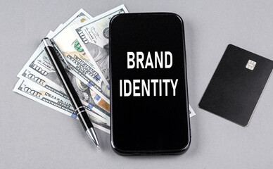 Credit card and text BRAND IDENTITY on smartphone with dollars and pen. Business concept