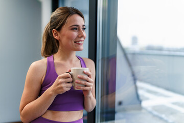Woman looking out the window, drinking coffee and enjoying her free time