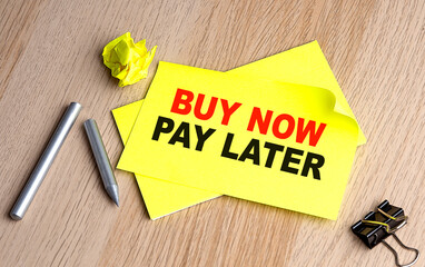 BUY NOW PAY LATER text on yellow sticky on wooden background