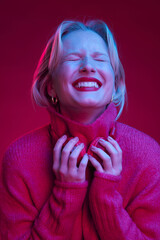 A happy woman is enjoying music while posing in studio isolated on magenta background. Viva magenta. - obrazy, fototapety, plakaty