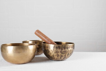 Tibetan singing bowls with sticks on white wall background
