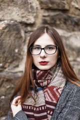 young woman in glasses wearing a coat wrapped in a scarf