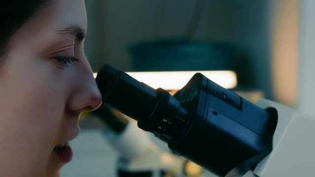 Close-up of the eyes of a researcher looking into a microscope. Research in the laboratory.