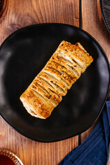 sausage in dough on a black plate on a wooden countertop