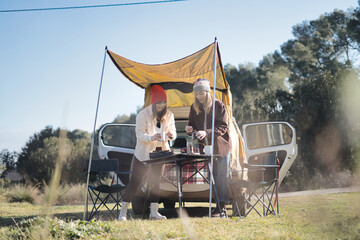 Young couple preparing breakfast outside the van. Winter vacations and relationship concept.