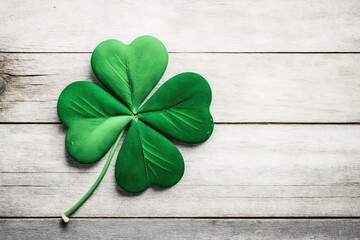 St.Patrick`s day background with felt four-leaf clover on white wooden table. Space for text, top view. Lucky irish shamrock