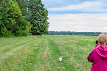 Dziewczyna w fioletowej bluzie, z psem, na spacerze na skraju lasu robi zdjęcia swojemu psu 