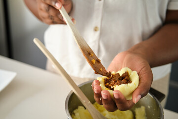 Close up of cuban woman hands filling mashed potatoes with minced beef to prepare cuban style...