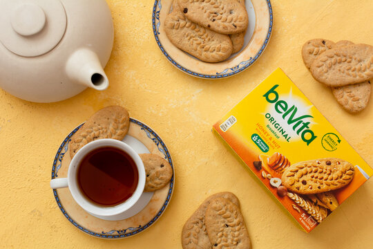 Tiraspol, Moldova - January, 31, 2023: BelVita breakfast cookies box with smak Honey and Nut with choc chips, cookies on plate and tea on orange background. Selective focus, top view