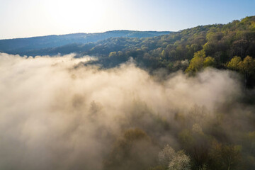 Fog covers the mountain forest. Mountain inversion. Highlands under the fog. Foggy sunrise in the mountains. Aerial view of fog-covered forest.