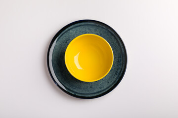 Plates on the white background. yellow bowl on a blue plate.