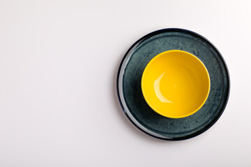 Plates on the white background. yellow bowl on a blue plate.