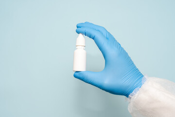 Plastic small bottle in doctors hand. Eye, ear or nose drops