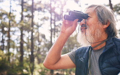 Binoculars, senior man and hiking in nature looking at view, sightseeing or watching. Binocular,...