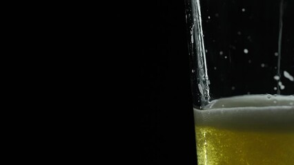light beer being filled up in a glass showing carbonation and bubbles on a black background