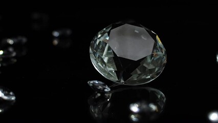 A slow turning diamond with smaller diamonds on a dark shiny surface to indicate luxury or wealth or as a gift for special occations like weddings valentines day.