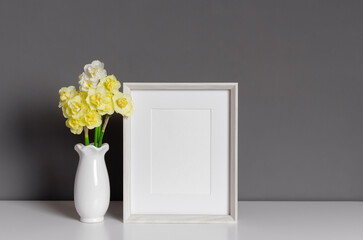 Blank white photo frame mockup with yellow flowers in vase, blank frame with copy space