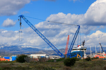 Fototapeta na wymiar View of cranes and other port equipment in front of snowy mountains and cloudy sky, Limassol New Port, Cyprus 