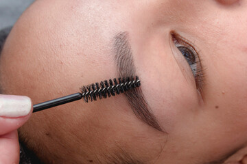 An esthetician using a eyebrow brush to gently shape the brows of a customer after a microblading procudure.