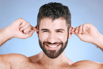 Cleaning, ear and man with cotton bud in studio for hygiene, grooming and beauty routine on blue...
