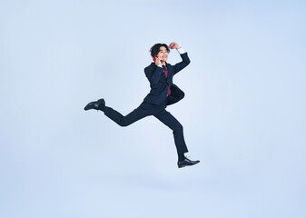 Fototapeta na wymiar スマホで通話しながらジャンプする若いビジネスマン