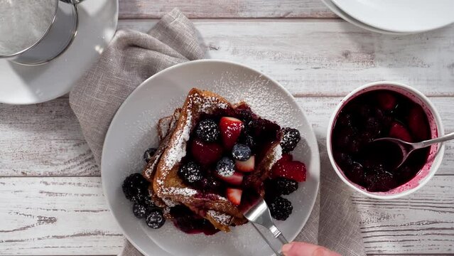 Time lapse. Step by step. Easting freshly made french toast with mix berry compote and powder sugar.