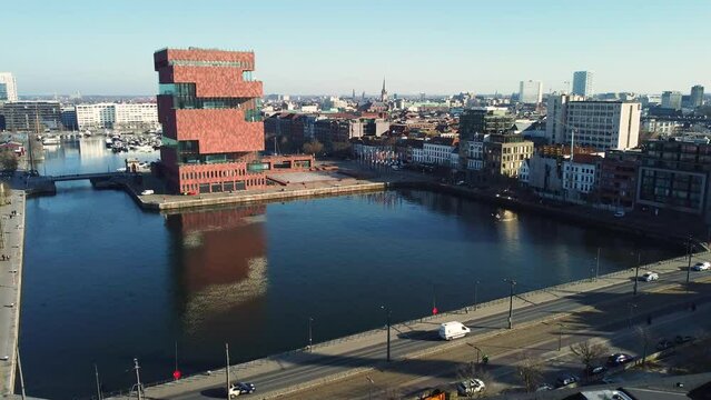 Establishing shot flying over rooftops and showing the Antwerp MAS museum, road traffic and the city in the background. Drone aerial 4k shot
