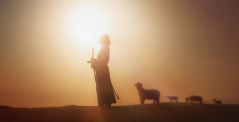 Shepherd Jesus Christ leading the sheep and praying to God and in the field bright sun light and Jesus bokeh silhouette background
 - obrazy, fototapety, plakaty