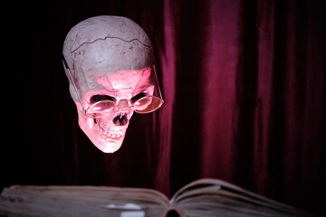 Skull with glasses and an old open book. Mystic and horror concept. Selective focus.
