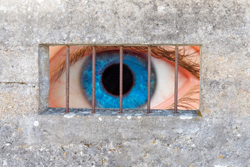 An blue  eye behind prison bars
