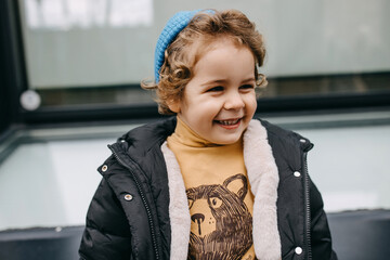 Portrait of a little happy boy with blonde curly, smiling, outdoors.