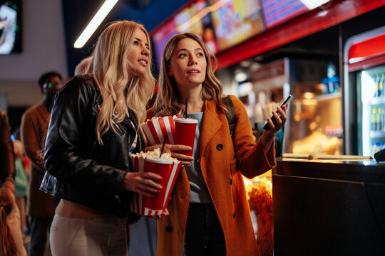 Joyful girlfriends going to movies.