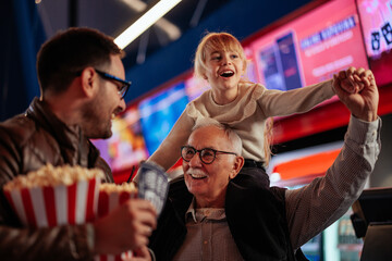 Joyful senior man with son and granddaughter at movies.