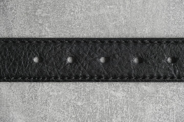 Black leather belt gray concrete background.