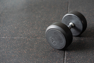 Obraz na płótnie Canvas Black dumbbell. Weight Training Equipment. black dumbbells on the floor in dark concept fitness room with training equipments