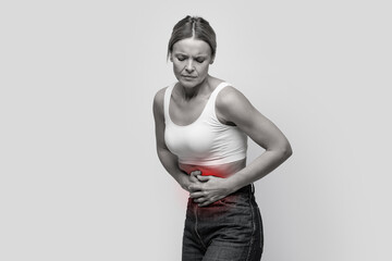 Woman with abdominal pain in white top. Diarrhea Gray background