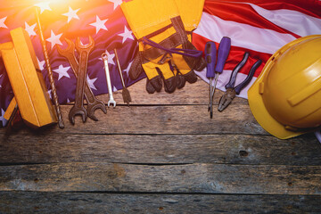 Flag America and construction tool on wooden background are illuminated by sunlight.Concept Labor Day first May.