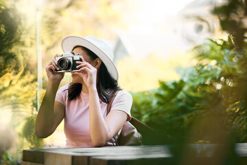 Fototapeta na wymiar Photography, memory and woman with a camera in nature during travel in Singapore. Vacation, tourism and professional ecology photographer in a botanical garden to capture the natural environment