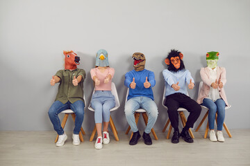 Group of young people in trendy rubber masks of different animals' heads showing thumbs up. People...