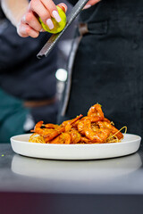 chef cooking fried big shrimps with seasonings in plate on kitchen