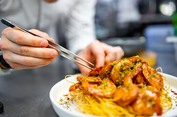 chef cooking fried big shrimps with seasonings in plate on kitchen