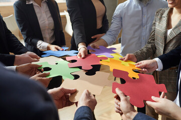 Group of businesspeople connecting jigsaw puzzle. Creative business team come up with lots of ideas and suggest different solutions to problem. Cropped close up shot. Teamwork and innovation concept