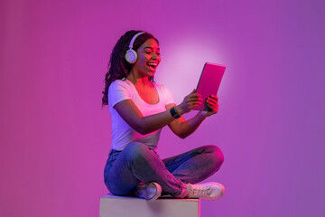 Virtual Content. Excited Black Female Relaxing With Digital Tablet In Neon Light