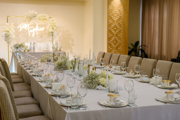 Wedding banquet decoration in hall restaurant. Wedding setup. Luxury wedding reception. Festive arch decorated composition flowers and candles. Table covered a tablecloth in party area. Table setting.