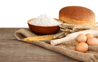 Wheat ears and flour on wooden background