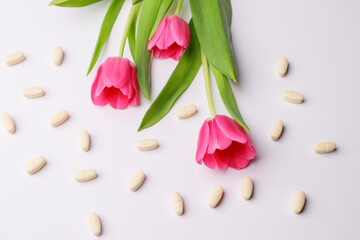 Fototapeta na wymiar Vitamins pills on a white background and tulips